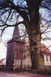 Za dębem - kośció z zabytkową XVII w. dzwonnicą wieżową
